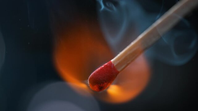 Match Igniting In Macro, Red Sulfur-Potassium Head Combusts And Emits Smoke Rising on a Blue Background