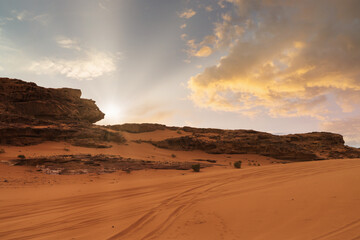 Fototapeta premium Sunset over a red desert landscape with sandy terrain and rock formations. Wadi Rum, Jordan.