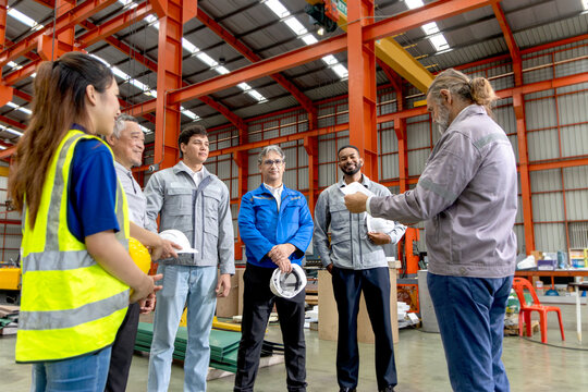 Supervisor of diverse engineers briefing his team before working in manufacturing factory. Leader giving a briefing to team in industrial site. Worker manager conducting a site meeting in a factory.