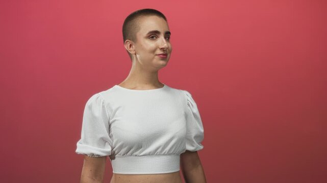 Woman with buzz cut showing bare midriff, open mouth gesture and head turned to right in studio; surprise.