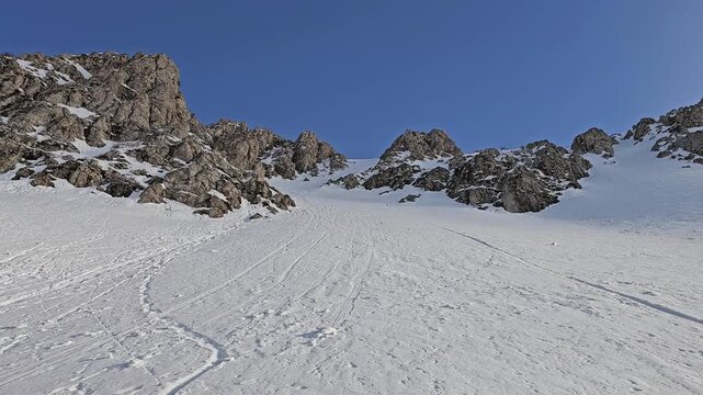 Snow-covered mountain slope with natural snow slide marks on the steep terrain under a clear blue sky in a bright winter alpine landscape.  
📍Hawraman Takht, Kurdistan 