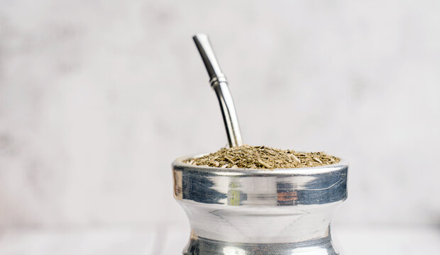 Traditional yerba mate prepared in palo santo matero with bombilla placed on rustic wooden surface. Natural energy drink concept, minimalist lifestyle and South American herbal ritual.
