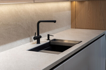 Matte black kitchen sink and faucet on gray stone countertop
