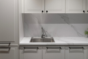 Stainless steel sink with chrome faucet on white marble countertop