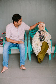 Man gently touches head of young girl in traditional Muslim prayer attire