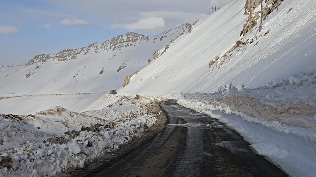 snowy mountain road winding through a bright winter landscape, dark asphalt contrasting with white snowbanks, rocky cliffs, and clear blue sky.  
📍Hawraman Takht, Kurdistan 