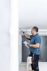 Construction worker plastering interior wall near window
