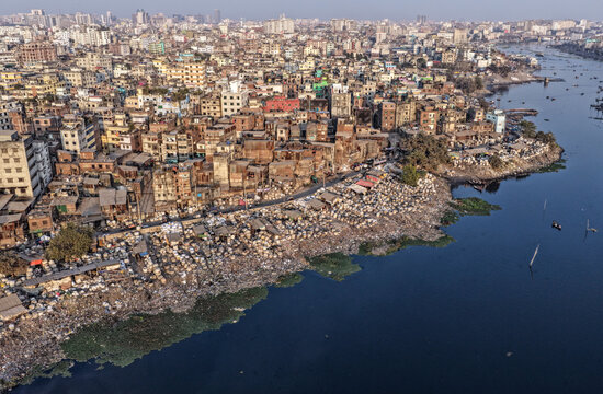 Dhaka, Bangladesh - 05 February 2026: Aerial view of densely packed buildings meet the polluted riverbank, a stark contrast of urban sprawl and environmental concern.