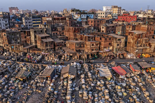 Dhaka, Bangladesh - 05 February 2026: Aerial view of a vast expanse of waste sprawling beneath a dense urban landscape, textures of poverty juxtaposed against the city's skyline.