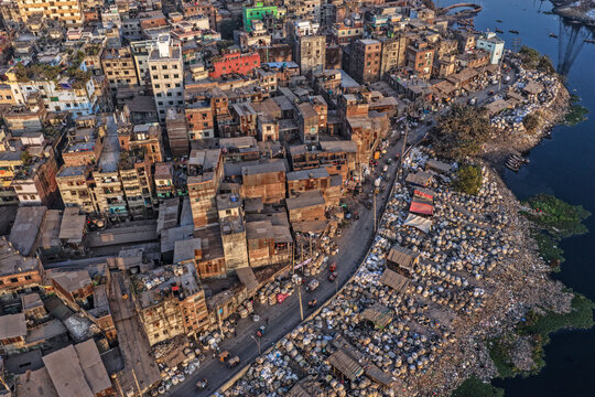 Dhaka, Bangladesh - 05 February 2026: Aerial view of a densely populated urban area, where buildings meet a riverbank marred by piles of waste, creating a stark contrast.