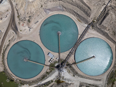 Aerial view of three circular turquoise ponds interconnected by pathways amid the arid landscape, contrasting sharply with the surrounding desert terrain, Clarkdale, Arizona, United States.