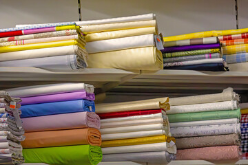 Colorful fashion material rolls on shelf of fabric store interior