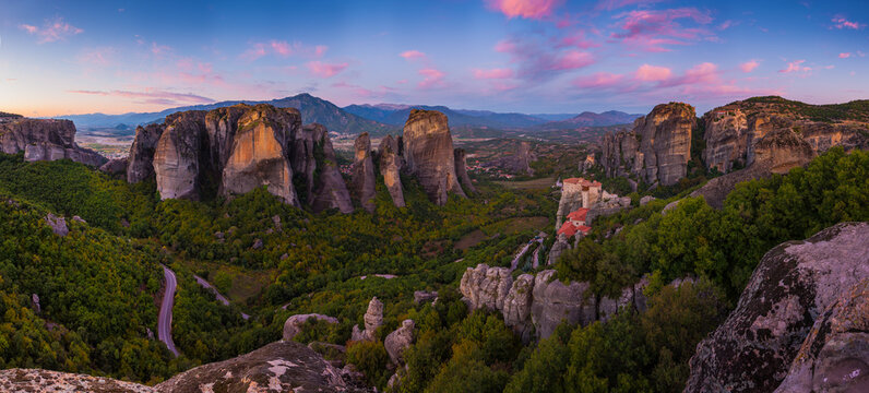 Aerial view of imposing rock formations crowned with monasteries against a backdrop of pastel sky, Kalabak, Trikala, Greece.