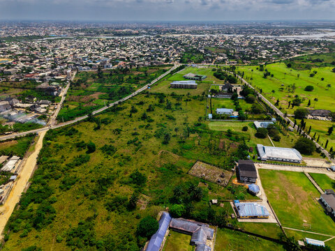 Aerial view of the diverse landscape with a mix of urban development, green spaces, and scattered buildings, a tapestry of textures and tones, Port Harcourt, Rivers, Nigeria.
