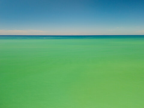 Aerial view of abstract seascape, luminous turquoise waters dissolve into a serene blue sky, minimalist natural background with a seamless horizon, Santo Stefano, Sicily, Italy