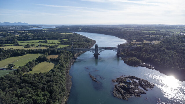 Aerial view of a bridge standing tall over the shimmering waters, a testament to engineering amidst the wild embrace of nature, Bangor, United Kingdom.