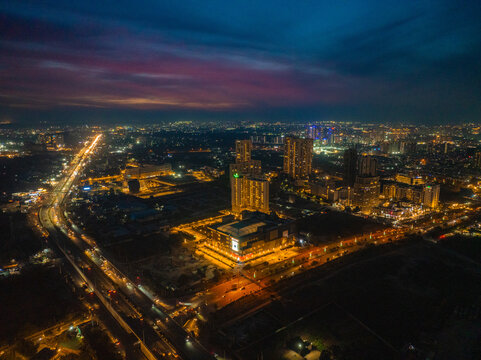 Aerial view of the vibrant city lights illuminating the skyline as dusk settles over the buildings and roads, Gurugram, Haryana, India.
