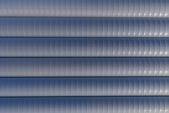Aerial view of a series of metallic, horizontally aligned tubes, their surfaces reflecting light in a patterned, linear design, Tredarzec, Bretagne, France.