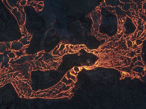 Aerial view of molten lava flows like fiery rivers across the dark landscape, a dance of destruction and creation, Grindavik, Grindavikurbaer, Iceland.