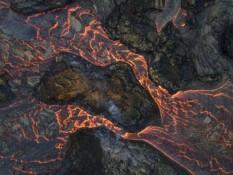Aerial view of fiery rivers of molten lava carve paths through the dark, rugged landscape, a raw display of nature's power, Grindavik, Grindavikurbaer, Iceland.