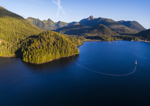 Aerial view of a commercial purse seine salmon fishing boat, with its net deployed, off the mountainous coast of Sitka, Alaska