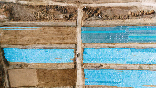 Aerial view of geometric patchwork of blue tarps and bare earth, creating a striking contrast in the agricultural landscape, Sremska Mitrovica, Vojvodina, Serbia.