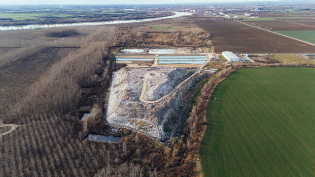 Aerial view of a sprawling landfill contrasts with the green fields nearby, while the river meanders in the distance, Sremska Mitrovica, Vojvodina, Serbia.