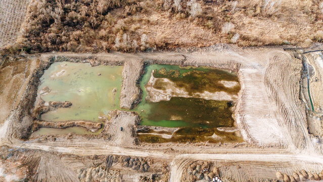 Aerial view of stagnant waters reflecting the sky amidst the earth tones, a stark contrast between the natural and the disturbed, Sremska Mitrovica, Vojvodina, Serbia.
