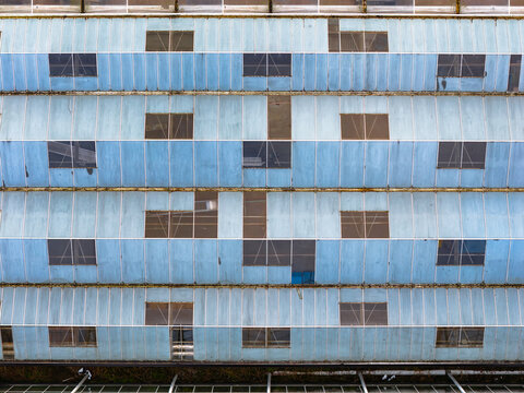 Aerial view of the building's facade with a pattern of windows and panels, showcasing a blend of light blue and gray tones, creating a textured surface, Tredarzec, Bretagne, France.
