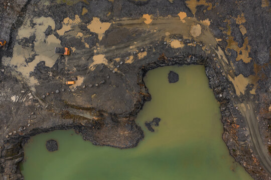 Aerial view of a quarry where the earth is scarred with deep gouges and standing water, Peumerit, Brittany, France.