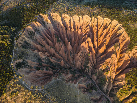 Aerial view of the eroded landscape reveals a symphony of textures, where earthy tones blend with sun-kissed peaks, creating a rugged charm, Valdepenas de la Sierra, Castile-La Mancha, Spain.