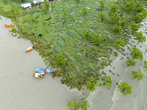 Aerial view of the landmass meets the water, dotted with vibrant boats and lush greenery, an intricate tapestry of life unfolds, Chattogram, Chittagong Division, Bangladesh.