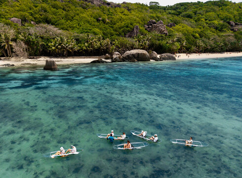 Aerial view of the translucent turquoise waters reveal the ocean floor as boats float peacefully near the shore, Anse Reunion, La Digue, Seychelles.
