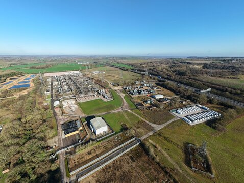 Aerial view of the National Grid Sundon Substation where the silver structures contrast with the green fields under a clear sky, Luton, United Kingdom.