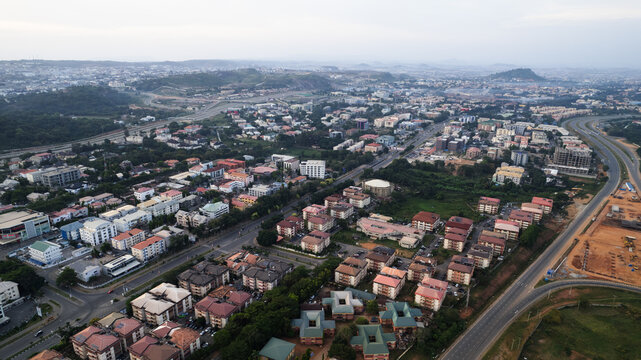 Aerial view of rooftops and tree-lined streets meet the horizon in a blend of urban and natural textures, Abuja, Federal Capital Territory, Nigeria.