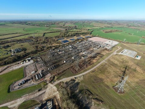 Aerial view of the National Grid Sundon Substation, where steel and concrete meet the soft green fields under a clear blue sky, Luton, United Kingdom.