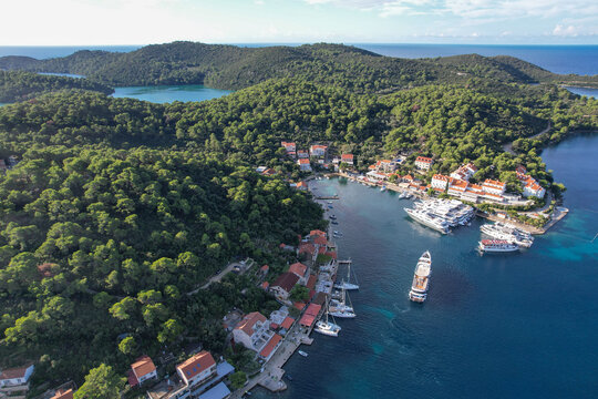 Aerial view of Pomena tranquil harbor nestled amidst Mljet National Park lush green hills, where boats bob gently on the turquoise water, Pomena, Dubrovnik-Neretva County, Croatia.