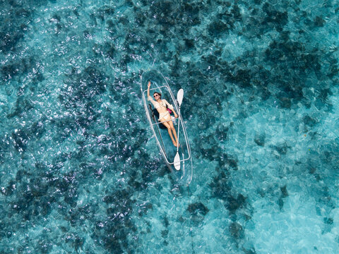 Aerial view of a person relaxing on a transparent kayak, the turquoise water shimmering like a thousand jewels, Anse Reunion, La Digue, Seychelles.