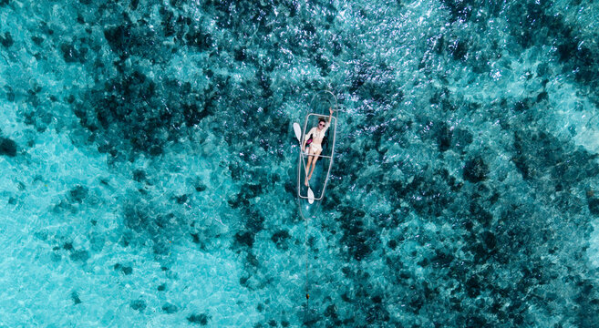 Aerial view of a person relaxing on a transparent kayak amidst the turquoise waters, Anse Reunion, La Digue, Seychelles.