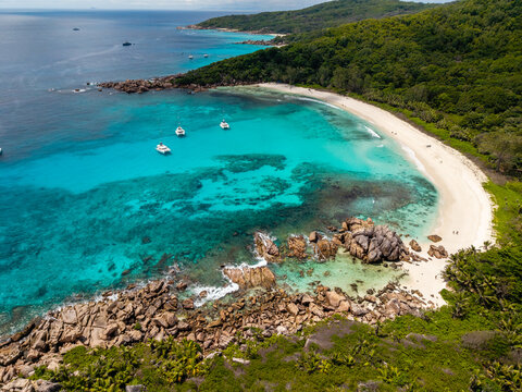 Aerial view of the turquoise waters contrasting with the white sands of the beach, surrounded by lush greenery, Anse Reunion, La Digue, Seychelles.