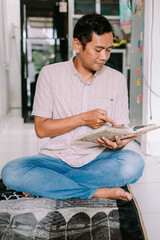 Dedicated Man Studying Holy Book on Prayer Mat at Home