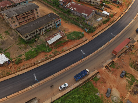 Aerial view of the newly paved road cutting through the heart of the city, contrasting with the older buildings and red soil, Ilesa, Osun, Nigeria.