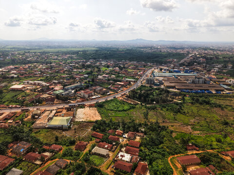 Aerial view of rooftops blending into the verdant landscape, a road cutting through the expanse of the city, Ilesa, Osun, Nigeria.