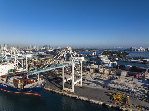 Miami, USA - 07 February 2026: Aerial view of a bustling port where vibrant cargo ships juxtapose with the stark industrial cranes against the city skyline.