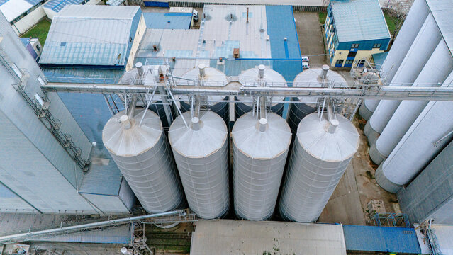 Aerial view of towering silver silos standing in stark contrast to the blue-roofed buildings, creating a textured industrial landscape., Sremska Mitrovica, Vojvodina, Serbia.