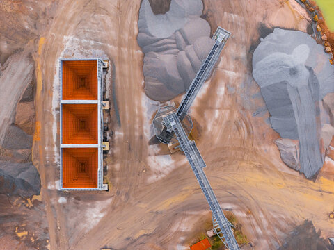 Aerial view of the industrial landscape, where rust-colored hoppers contrast against the varied grey tones of gravel piles and machinery, Gourlizon, Brittany, France.