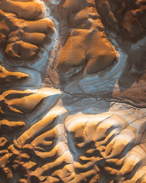 Aerial view of textured earth showing contrasting warm and cool tones, highlighting the intricate patterns etched into the landscape, Kyzylkum, Mangystau Region, Kazakhstan.