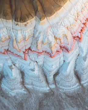 Aerial view of layered rock formations displaying a spectrum of earthy tones, from pale blues to rusty reds, creating a textured canvas, Aktau, Mangystau Region, Kazakhstan.