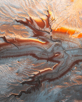 Aerial view of a tapestry of earthen tones weaves across the arid landscape, as winding paths carve through the terrain, Kyzylkum, Mangystau Region, Kazakhstan.
