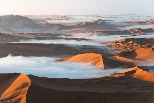 Aerial view of towering dunes kissed by ethereal mists, a symphony of ochre and pearl, Sossusvlei, Hardap Region, Namibia.